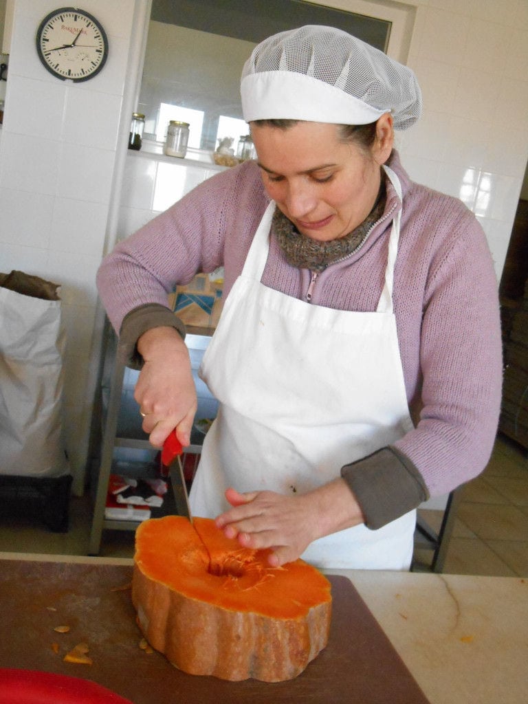 woman cutting a piece of yellow pumpkin with a knife at 'Agrotouristic Women's Cooperative of Mesotopos Lesvos'